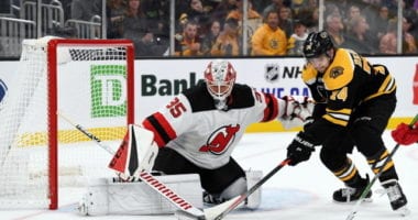 Jake DeBrusk of the Boston Bruins and Cory Schneider of the New Jersey Devils